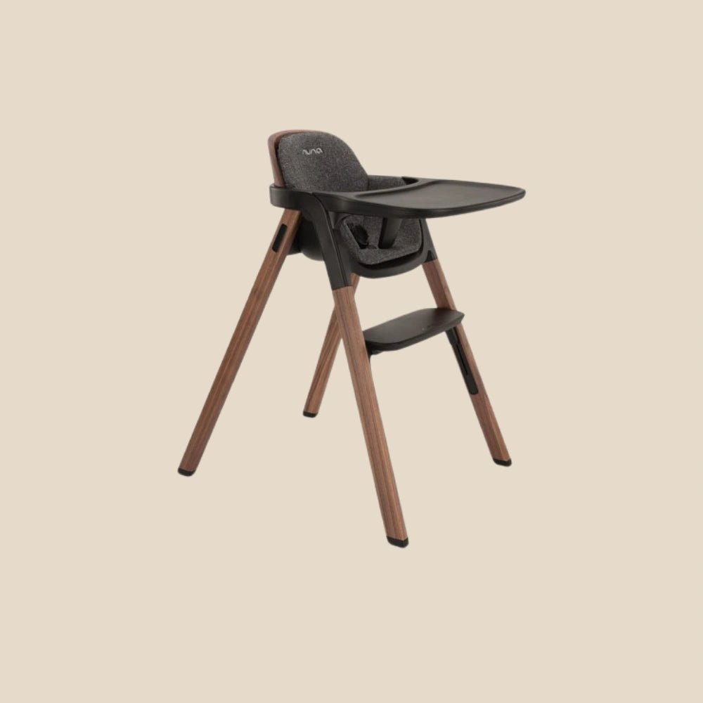 Baby high chair with wooden legs on a beige background